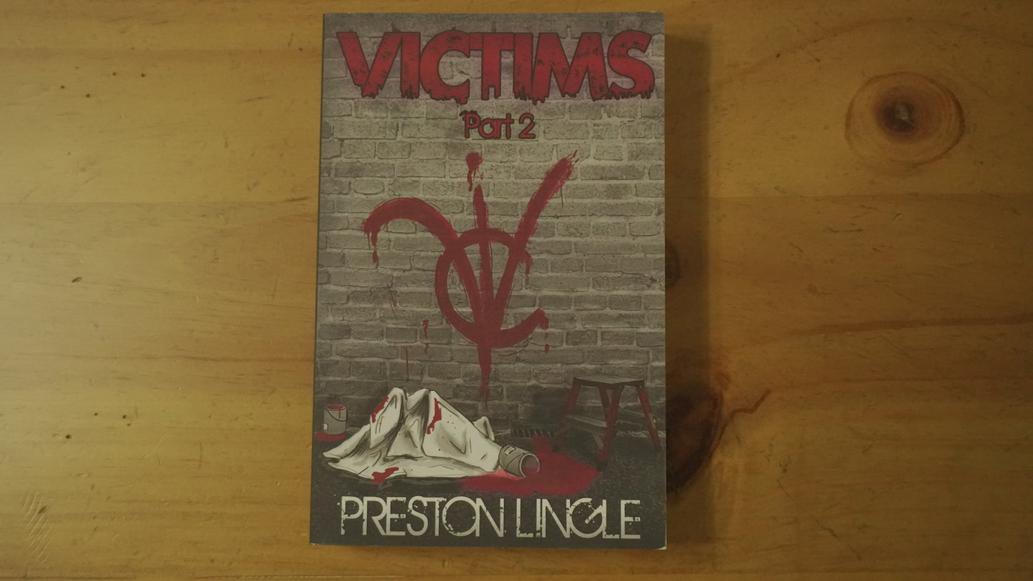 Front cover of the paperback version of the book titled 'Victims Part 2' by Preston Lingle on a wooden surface