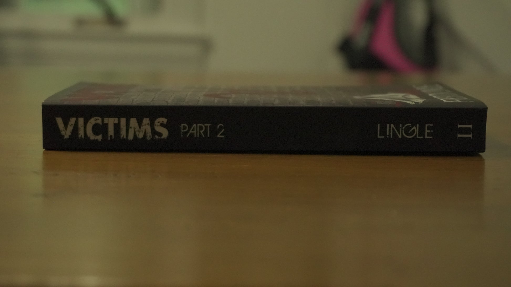 Book titled 'Victims Part 2' by Preston Lingle on a wooden surface with a blurred background