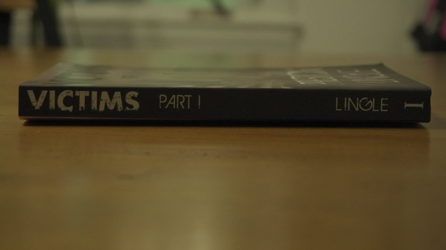 Book titled 'Victims Part I' by Preston Lingle on a wooden surface