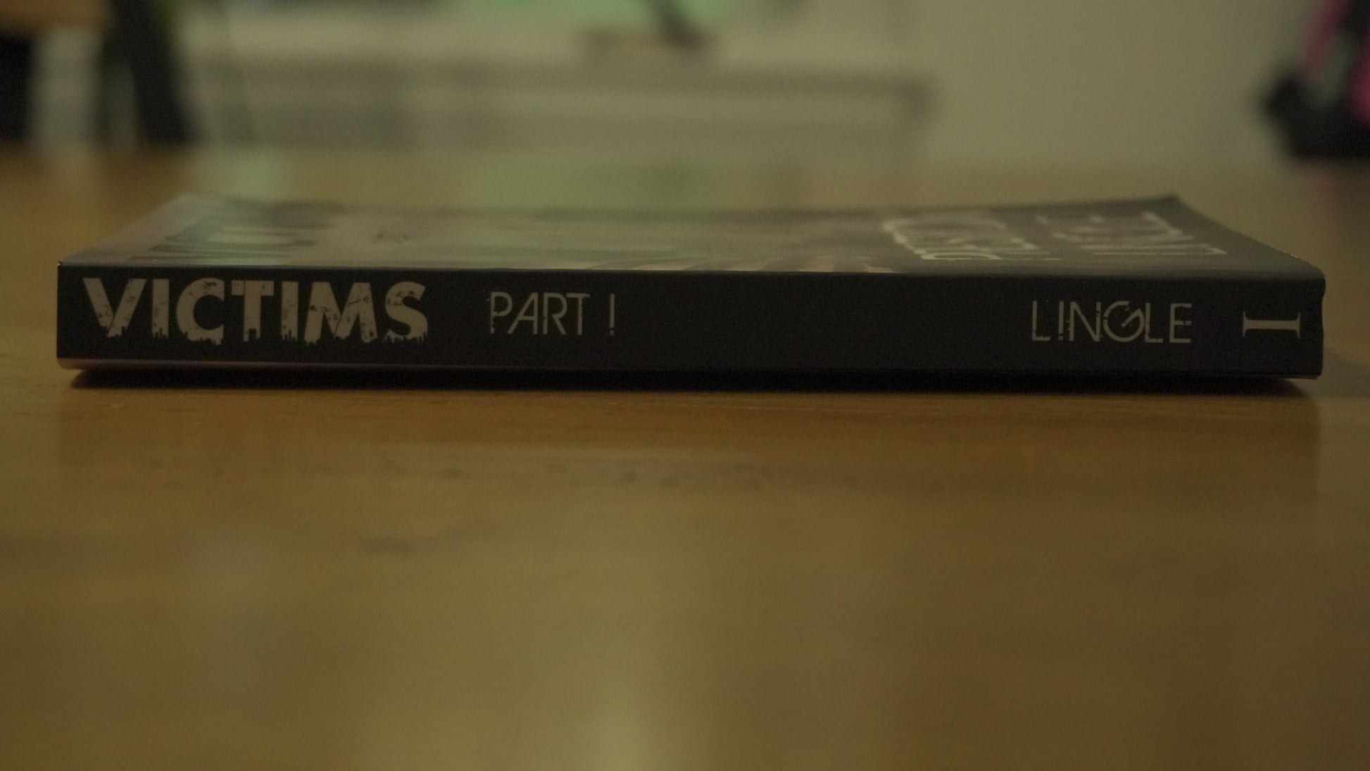 Book titled 'Victims Part I' by Preston Lingle on a wooden surface