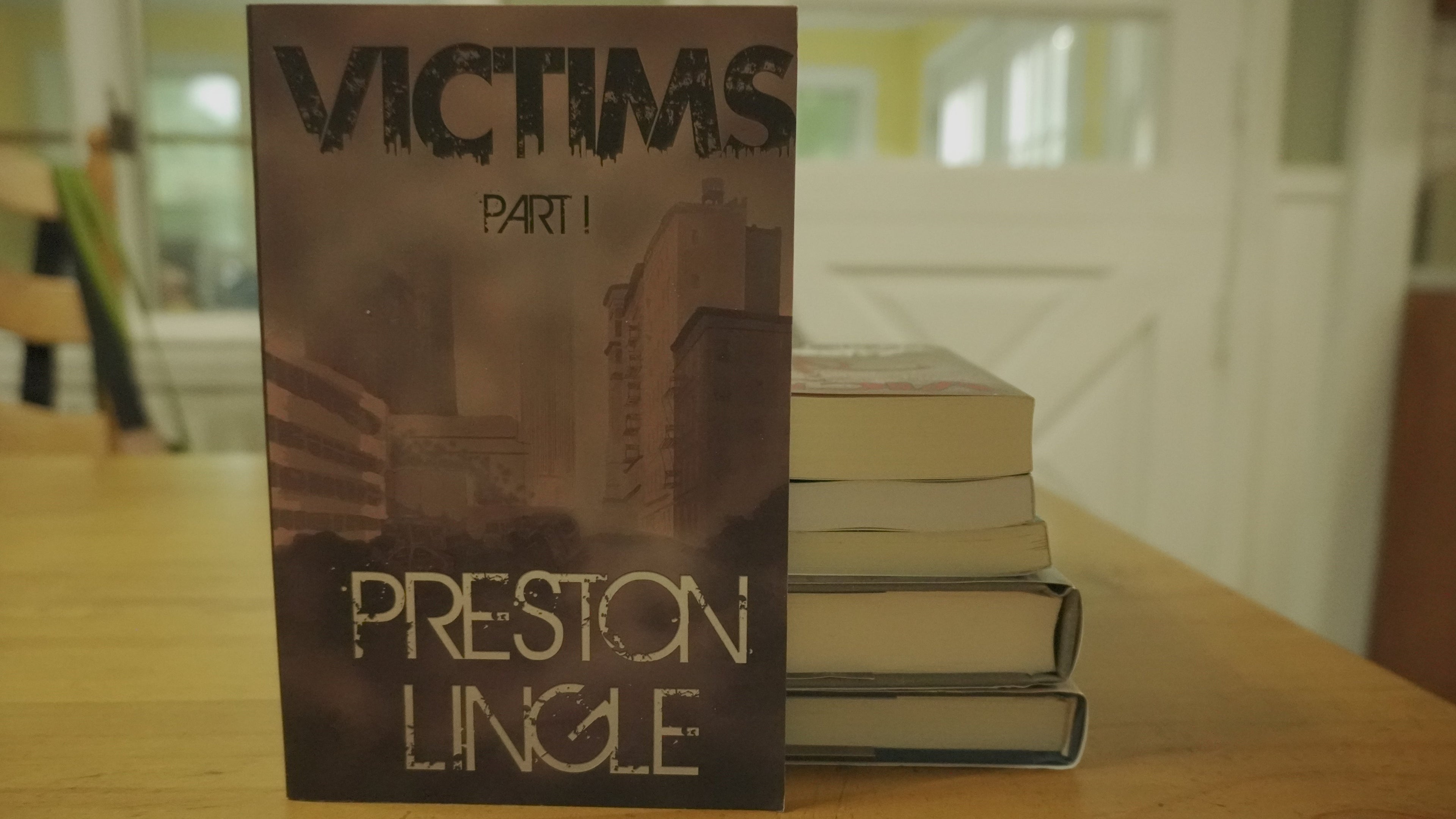 Book titled 'Victims Part 1' by Preston Lingle on a wooden table.